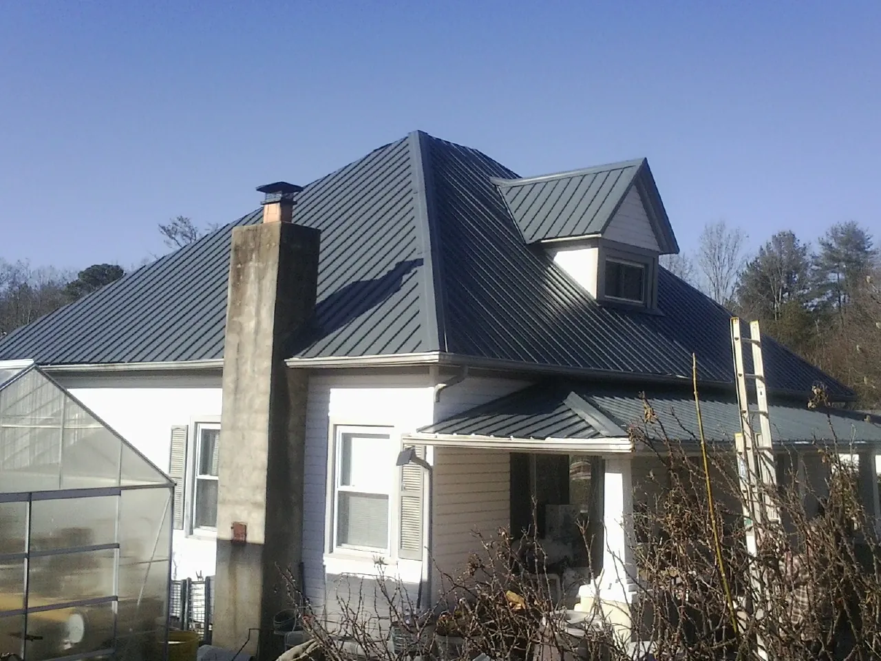 Dark blue standing seam metal roof on a white farmhouse with dormer — Slate & Tile Roof Repair by Roofing Brothers in Etna Green