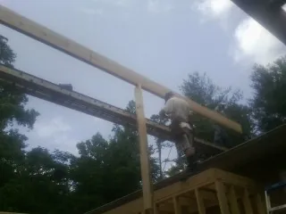 Carpenter setting a ridge beam over a new addition frame — Ice Dam Removal by Roofing Brothers in Etna Green