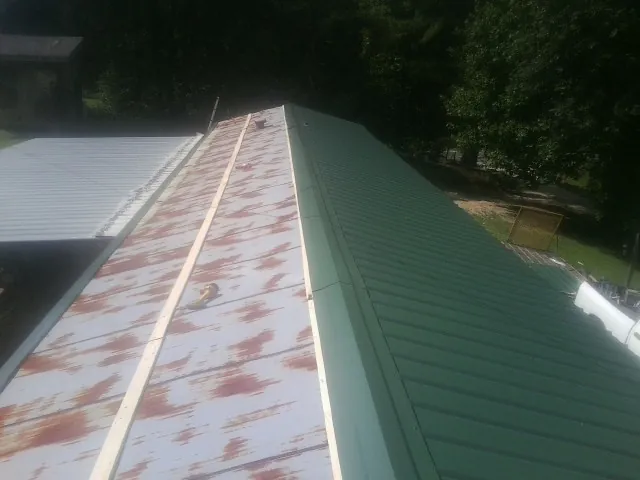 Old rusted panels beside newly installed green metal roofing — Wind Damage Roof Repair by Roofing Brothers in Etna Green