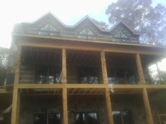 Dormers and porch framing on a large log home under construction — Roof Coating work by our crew in Etna Green