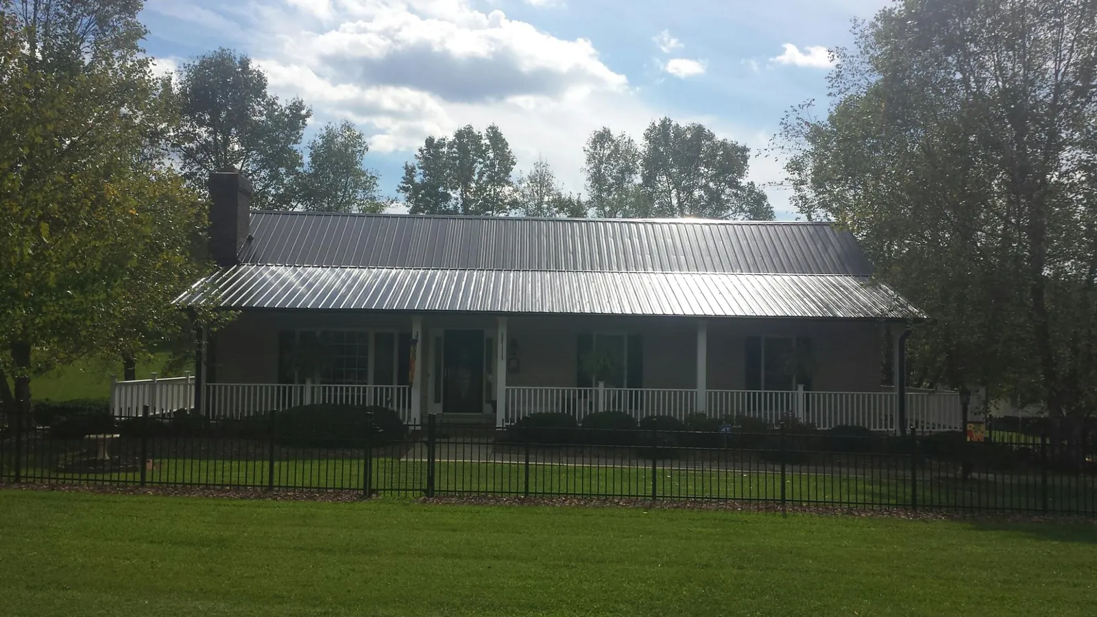 Gray metal roof on a brick ranch with a full width front porch — Gutter Guard Installation work by our crew in Etna Green