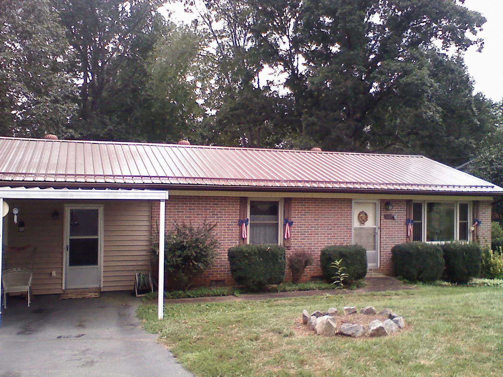 Bronze metal roof and carport on a brick ranch home — Roof Repair work by our crew in Etna Green
