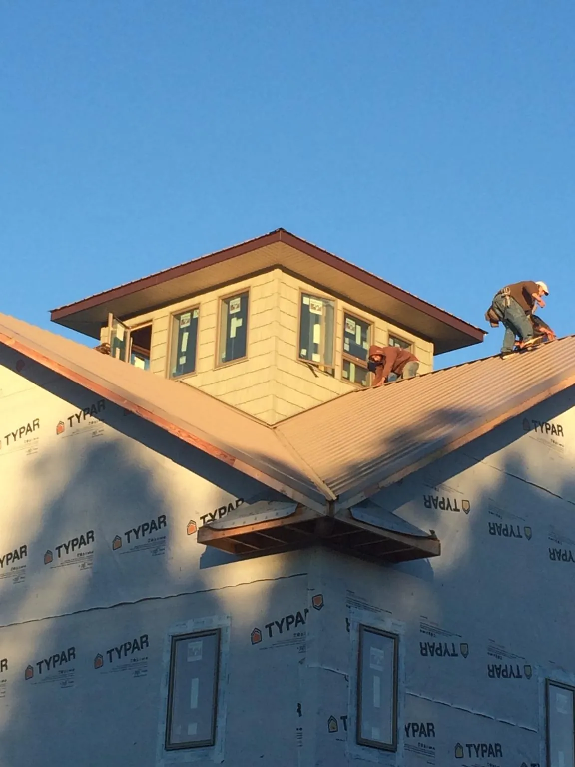 Roofers working around a rooftop cupola on a new metal roof at sunset — Roof Waterproofing in Etna Green by Roofing Brothers